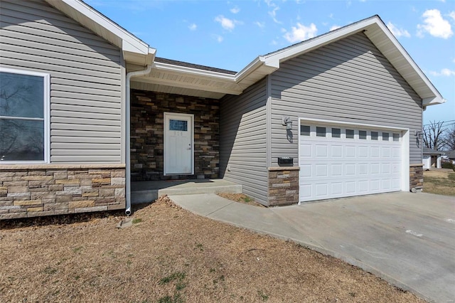 view of exterior entry featuring a garage, stone siding, and concrete driveway