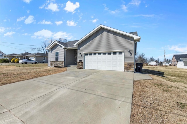 ranch-style home featuring an attached garage, stone siding, concrete driveway, and a front yard