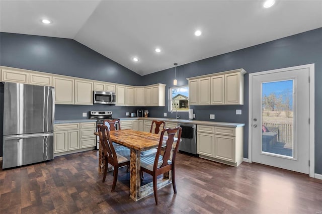 kitchen with vaulted ceiling, light countertops, appliances with stainless steel finishes, cream cabinetry, and dark wood finished floors