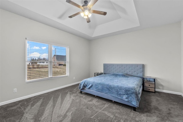 bedroom featuring ceiling fan, carpet, a raised ceiling, and baseboards