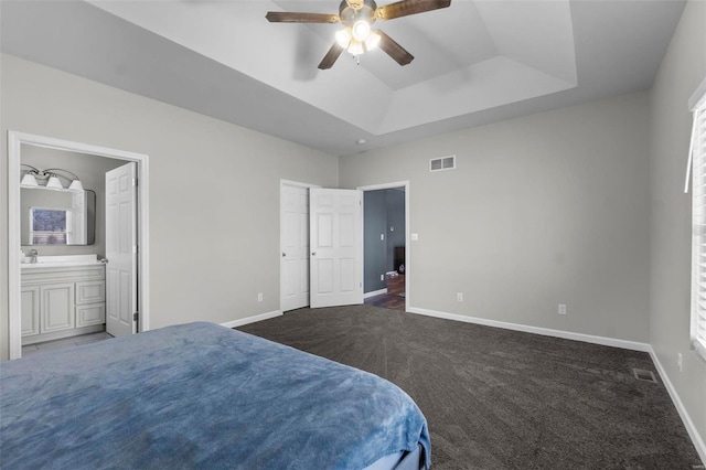 bedroom with dark colored carpet, a tray ceiling, visible vents, and baseboards