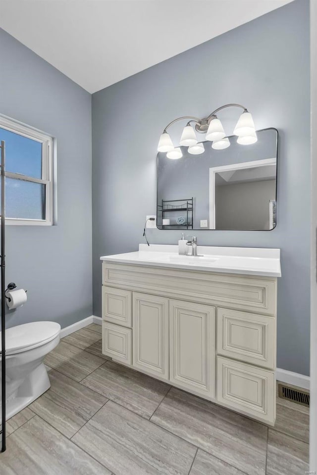 bathroom featuring toilet, visible vents, baseboards, and vanity