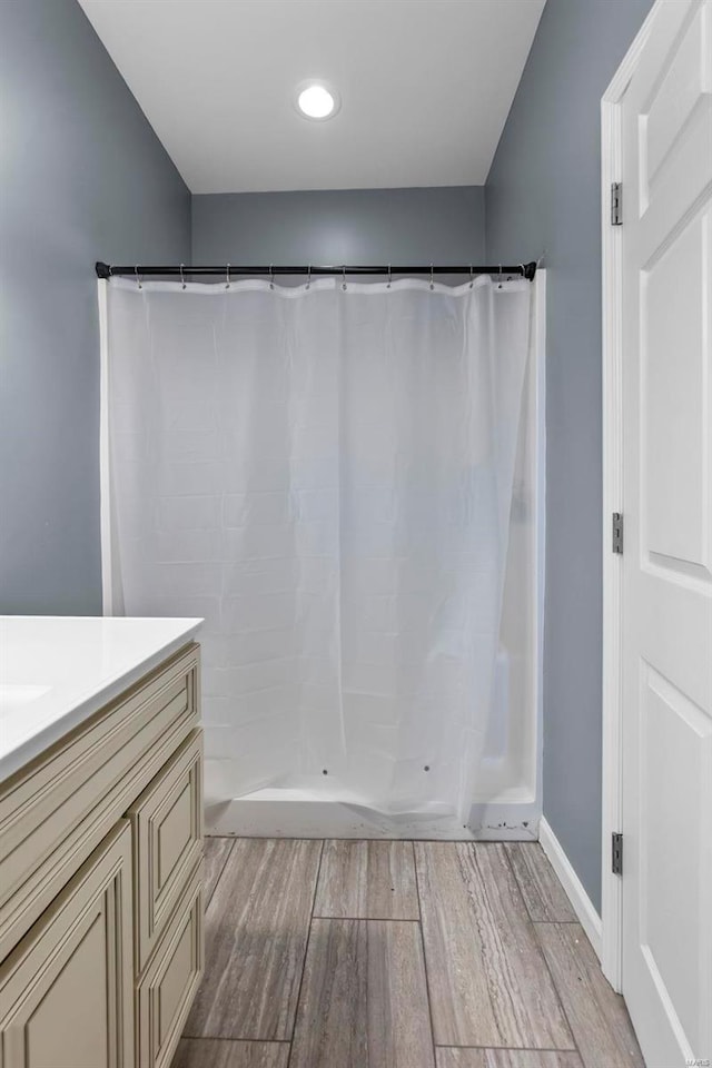 full bathroom featuring baseboards, wood finished floors, vanity, and a shower with curtain