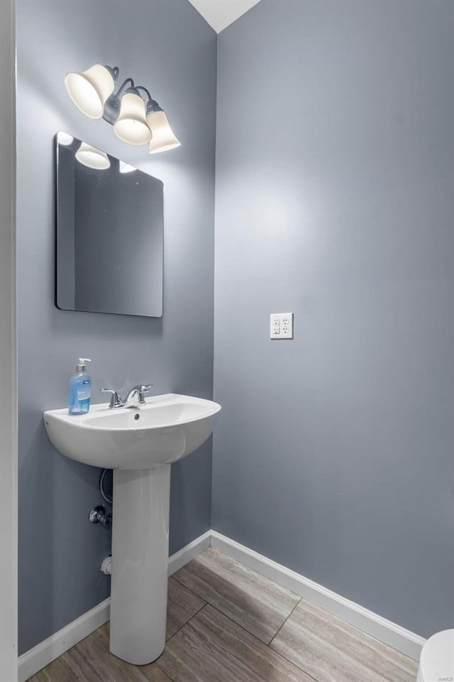 bathroom with a sink, wood finished floors, and baseboards