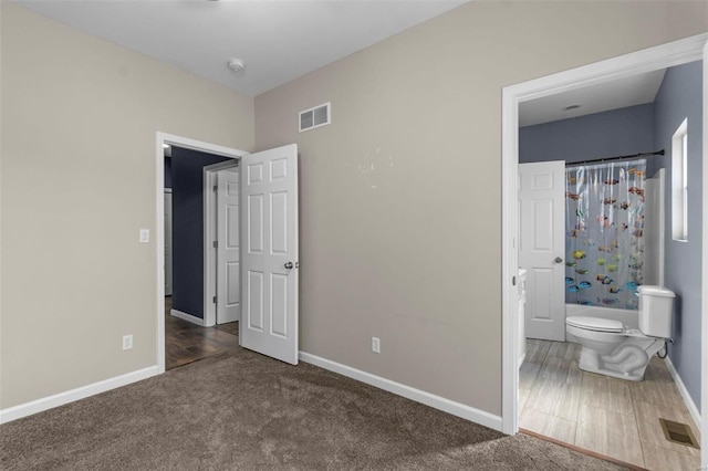 unfurnished bedroom featuring carpet floors, connected bathroom, visible vents, and baseboards