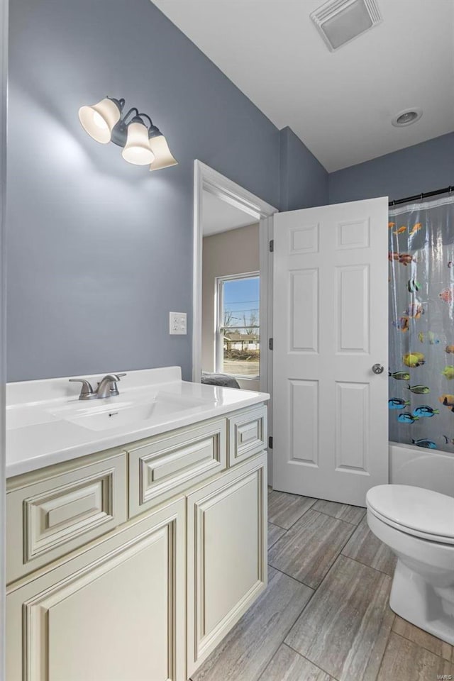 full bath featuring toilet, shower / tub combo, wood finish floors, vanity, and visible vents