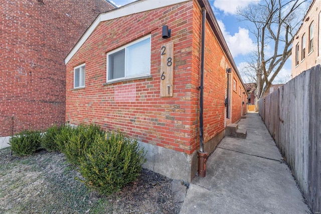 view of home's exterior featuring brick siding and fence