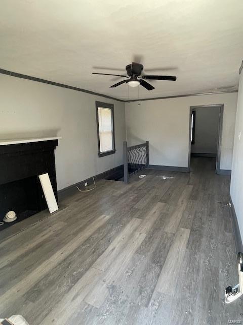 unfurnished living room with a ceiling fan, crown molding, baseboards, and wood finished floors