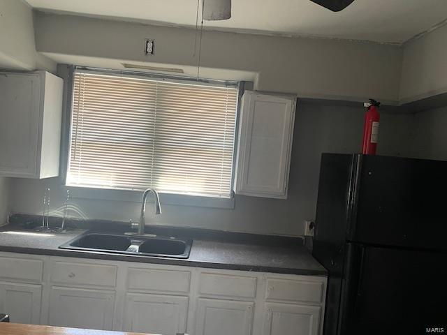 kitchen with freestanding refrigerator, white cabinets, a sink, and dark countertops