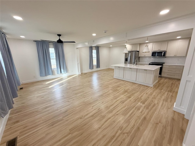 kitchen with stainless steel appliances, light countertops, open floor plan, and visible vents