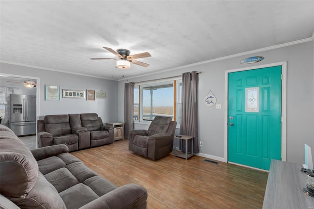 living room featuring visible vents, ornamental molding, ceiling fan, wood finished floors, and baseboards