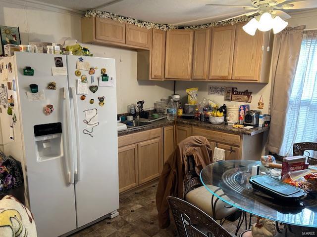 kitchen featuring ceiling fan, white refrigerator with ice dispenser, and dark countertops