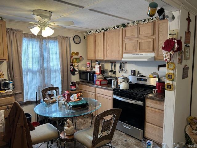 kitchen with dark countertops, light brown cabinetry, ceiling fan, gas range, and under cabinet range hood