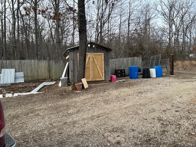 view of yard with fence, an outdoor structure, and a storage unit