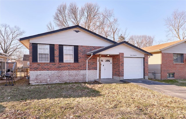 split level home with a garage, a front yard, brick siding, and aphalt driveway