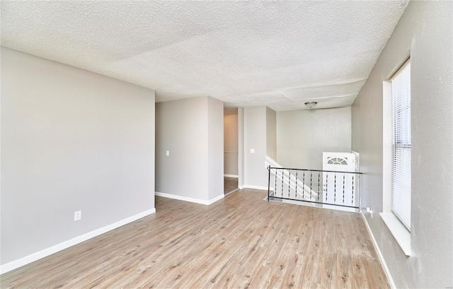 unfurnished room featuring a textured ceiling, wood finished floors, and baseboards