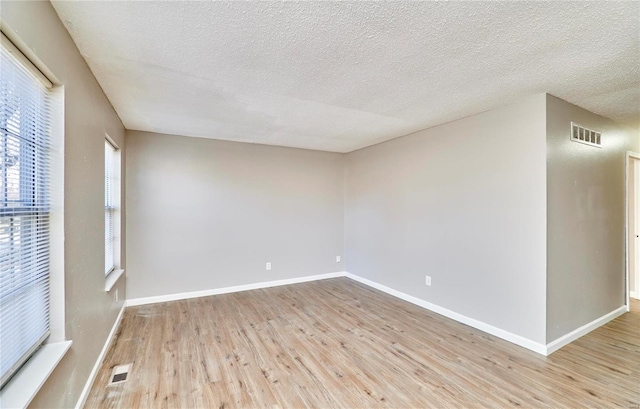 empty room with visible vents, baseboards, and wood finished floors