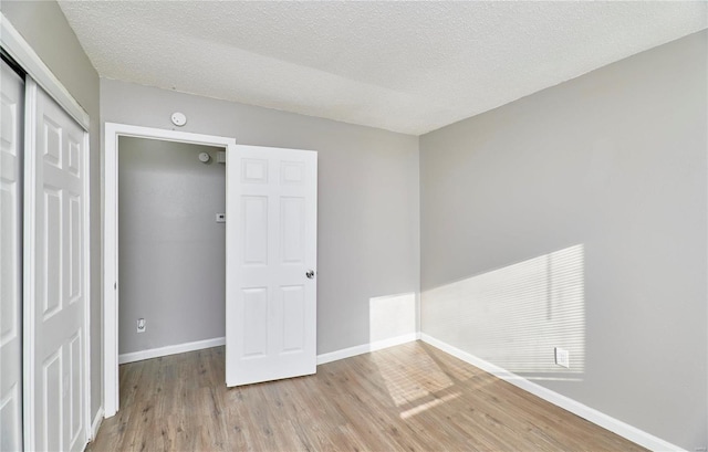 empty room with a textured ceiling, wood finished floors, visible vents, and baseboards