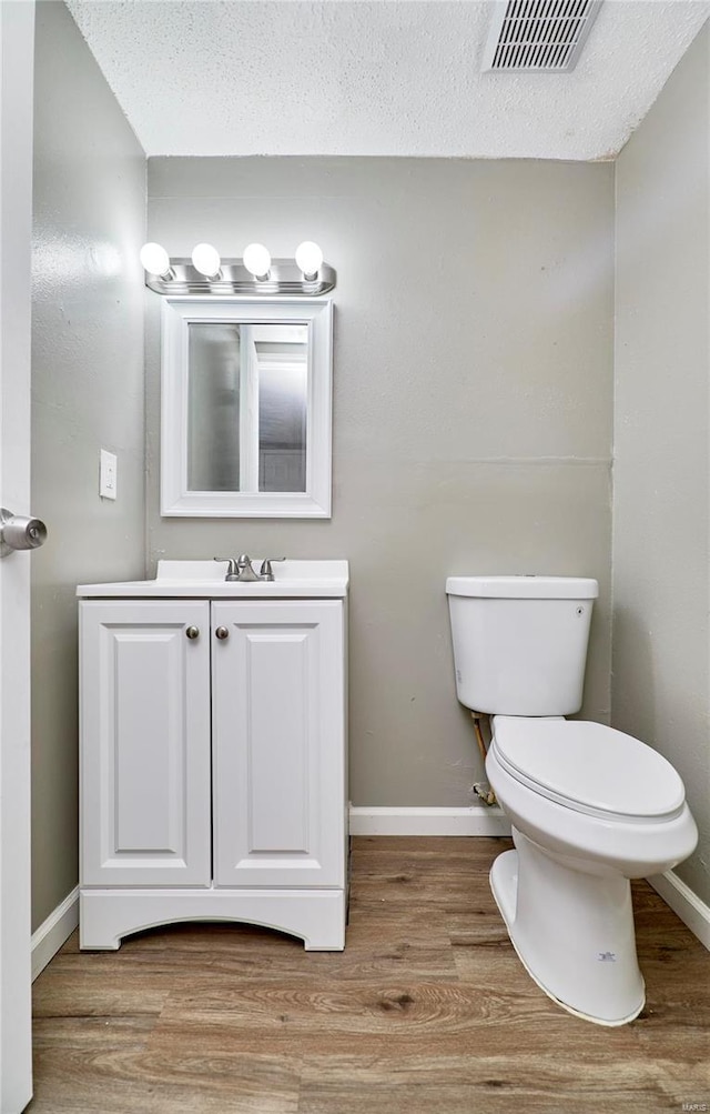 bathroom featuring toilet, baseboards, visible vents, and wood finished floors