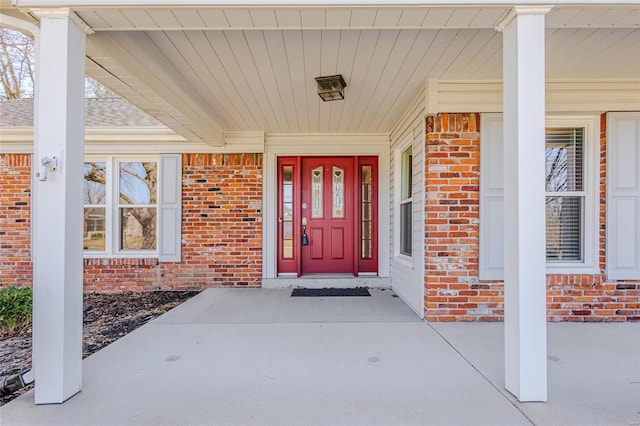 doorway to property with covered porch and brick siding