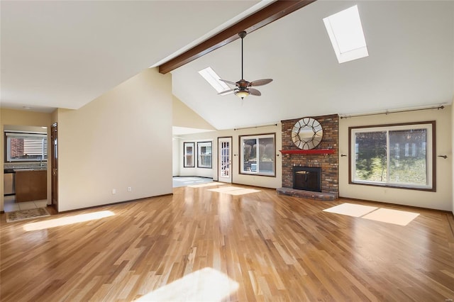 unfurnished living room with a skylight, a wealth of natural light, and beamed ceiling