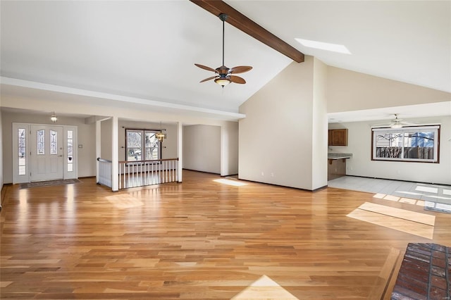 unfurnished living room featuring high vaulted ceiling, light wood-type flooring, beamed ceiling, and ceiling fan