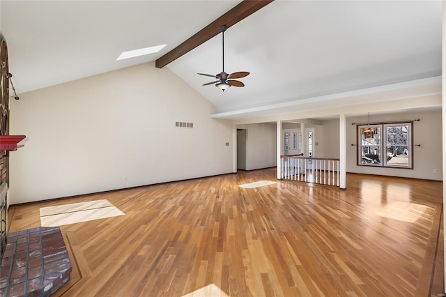 unfurnished living room featuring a skylight, visible vents, beamed ceiling, light wood-type flooring, and a fireplace