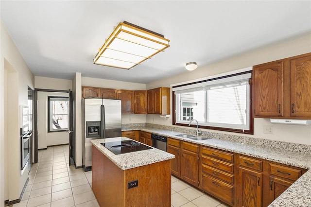 kitchen with light tile patterned floors, light stone counters, stainless steel appliances, a sink, and a center island