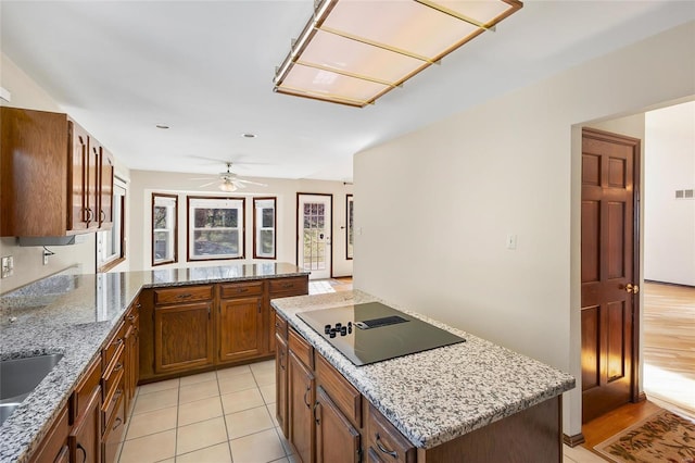 kitchen featuring visible vents, brown cabinetry, a kitchen island, a peninsula, and black electric stovetop