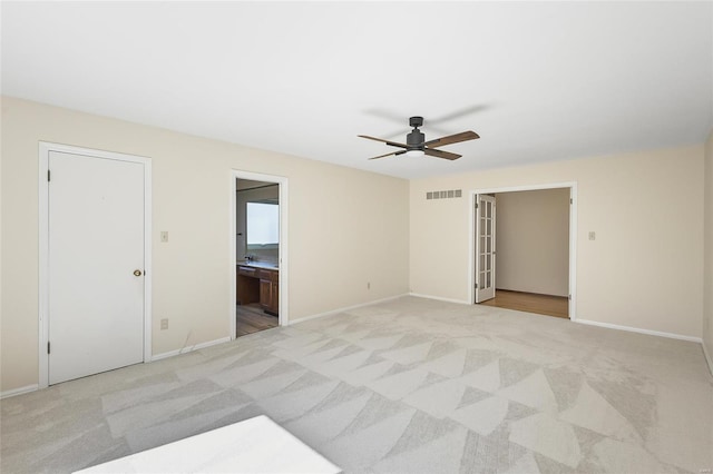 unfurnished bedroom featuring light colored carpet, visible vents, a ceiling fan, connected bathroom, and baseboards