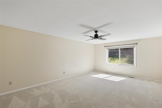 empty room with baseboards, a ceiling fan, visible vents, and light colored carpet