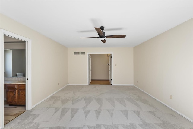 empty room featuring baseboards, visible vents, a ceiling fan, and light colored carpet