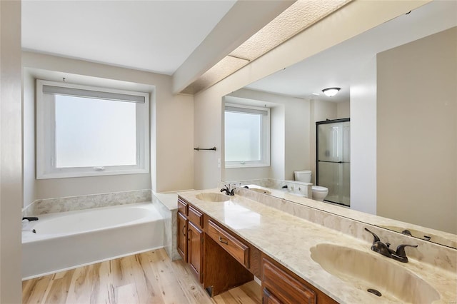 bathroom featuring a garden tub, toilet, wood finished floors, a sink, and a shower stall