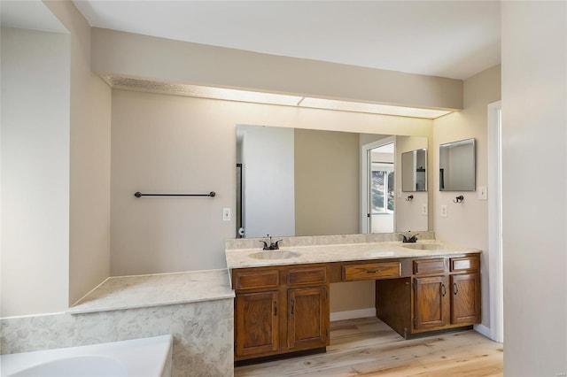 full bath with double vanity, a washtub, a sink, and wood finished floors