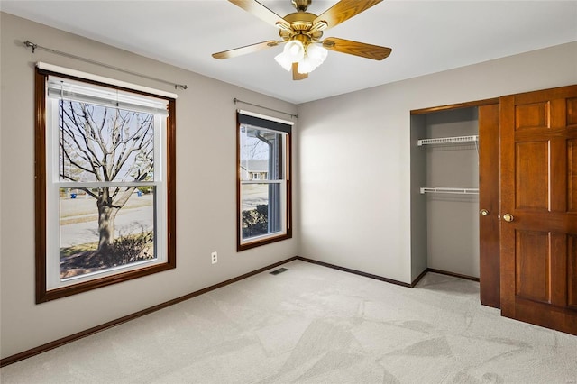 unfurnished bedroom with baseboards, visible vents, light colored carpet, ceiling fan, and a closet