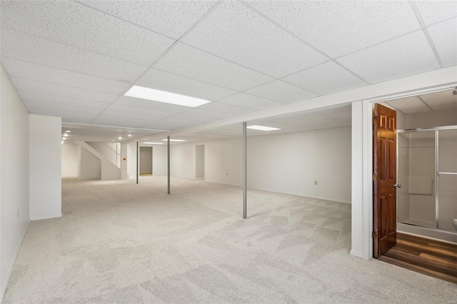 finished below grade area with carpet floors, baseboards, and a paneled ceiling