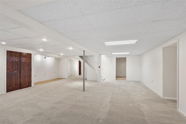 finished below grade area with carpet floors, recessed lighting, a drop ceiling, baseboards, and stairs