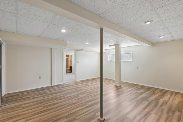 below grade area featuring a paneled ceiling, baseboards, light wood finished floors, and recessed lighting