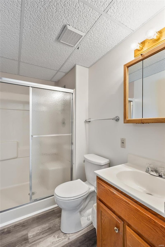 full bath featuring visible vents, toilet, vanity, a shower stall, and wood finished floors