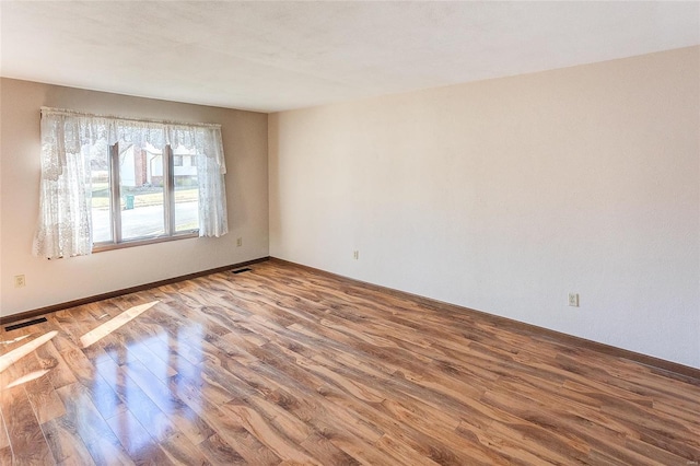 unfurnished room with visible vents and wood finished floors