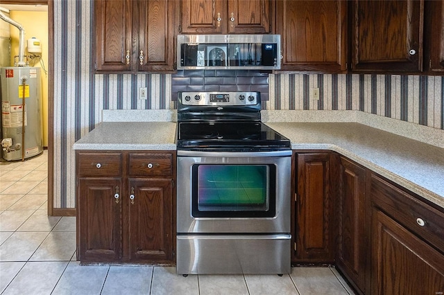 kitchen featuring wallpapered walls, appliances with stainless steel finishes, gas water heater, and light tile patterned flooring