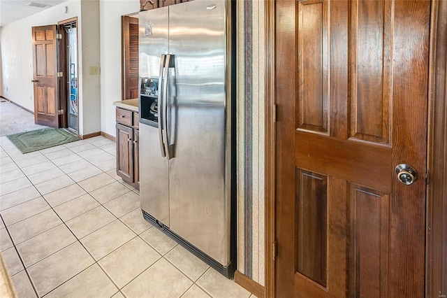 kitchen with light tile patterned floors, light countertops, stainless steel refrigerator with ice dispenser, and baseboards