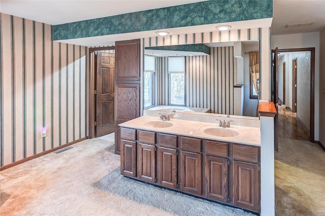 bathroom with wallpapered walls, baseboards, visible vents, and a sink