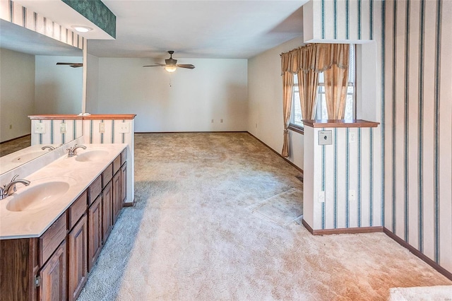 bathroom with ceiling fan, double vanity, a sink, and baseboards