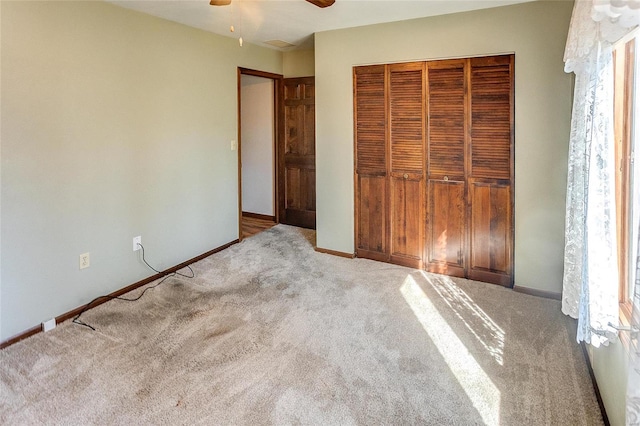 unfurnished bedroom featuring a ceiling fan, carpet, a closet, and baseboards