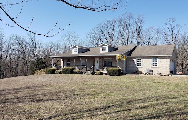 view of front of property featuring brick siding, covered porch, a front lawn, and roof with shingles