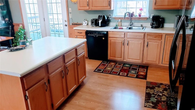 kitchen with light wood-type flooring, light countertops, black dishwasher, and a sink