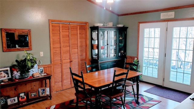 dining space featuring lofted ceiling, crown molding, wood finished floors, and a wainscoted wall