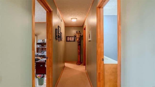 hall with baseboards, carpet floors, and a textured ceiling