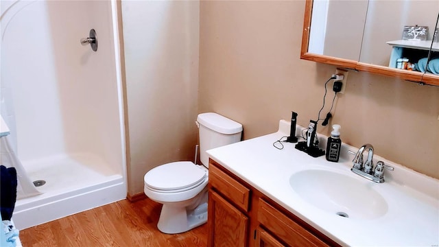 bathroom featuring a stall shower, toilet, vanity, and wood finished floors